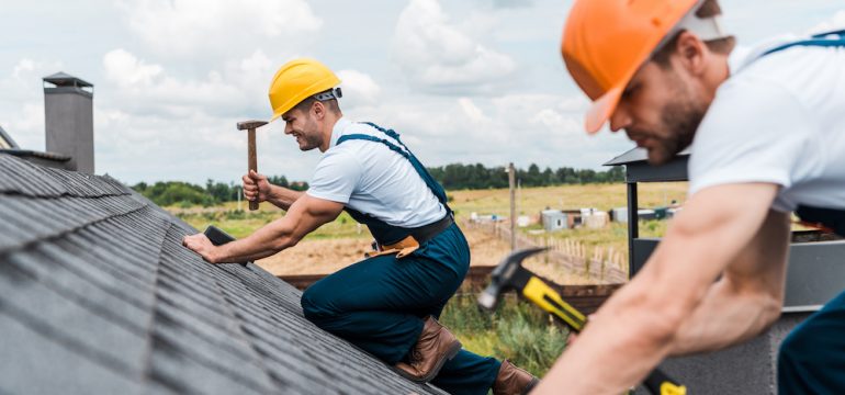 Focus of two handyman repairing a roof which is a major home system.