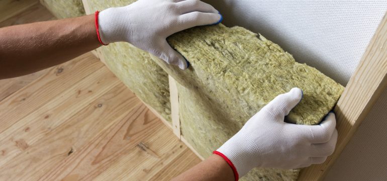 Close-up of worker hands in white gloves insulating rock wool insulation staff in wooden frame for future walls for cold barrier. Comfortable warm home, economy, construction and renovation concept.