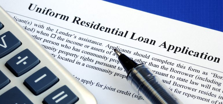 A mortgage loan application isolated on a blue background with a pen and a calculator.