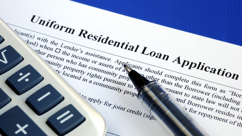 A mortgage loan application isolated on a blue background with a pen and a calculator.