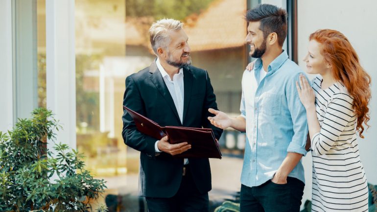 Smiling man and woman talking with landlord who is screening tenants for his investment rental property.