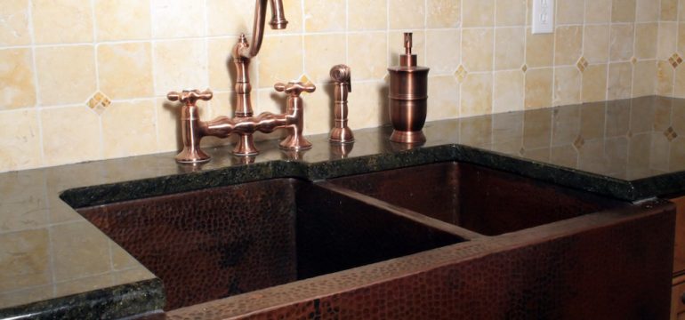 Kitchen sink made of copper materials set in a wood cabinet.