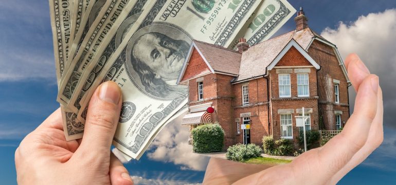 Hand holding house and money - sale of real estate