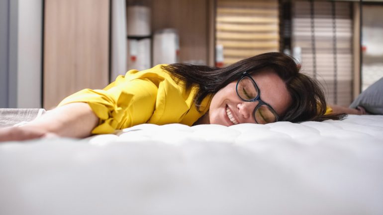 Buying a mattress to replace common household items. A brunette woman laying on a new mattress.