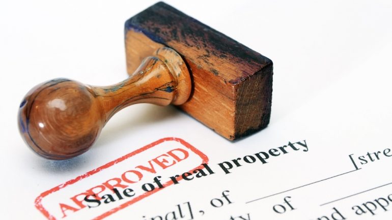 Sale of real property form with stamp of approval demonstrating transfer of clear title on a property.