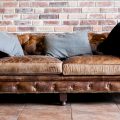 Vintage style of interior decoration with a leather sofa that needs cleaning in against a brick wall in a room.