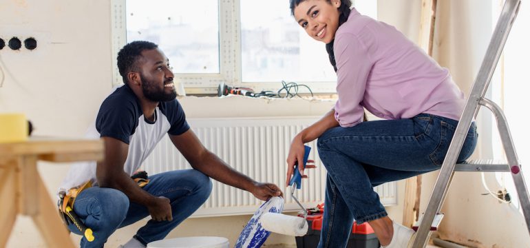 Happy young couple taking a break from painting their home.