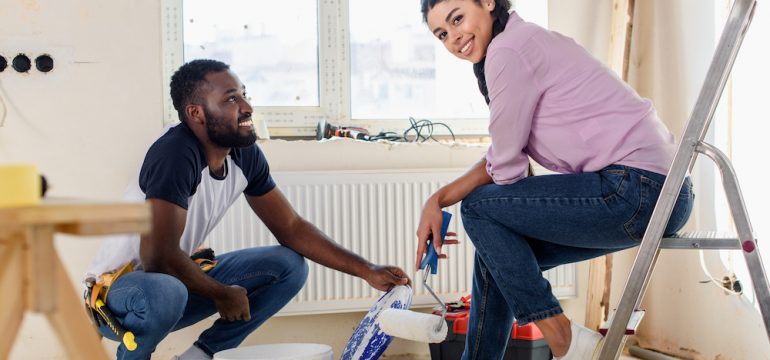 Happy young couple taking a break from painting their home.