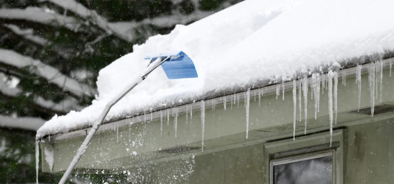 Removing snow off a house roof after a snowstorm.
