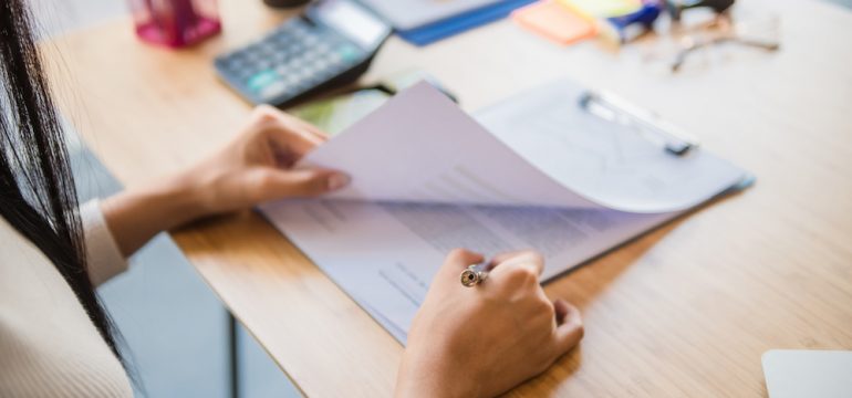 Woman sitting at a desk reviewing a title insurance policy for a new home.