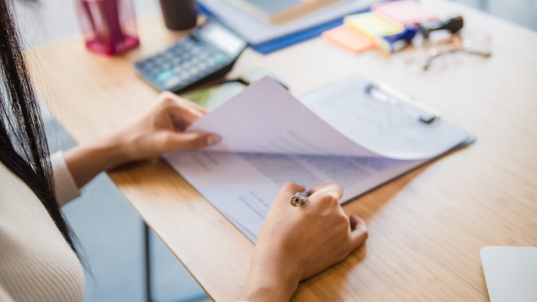 Woman sitting at a desk reviewing a title insurance policy for a new home.