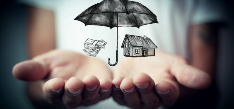 Open hands with an umbrella over a house and auto depicting coverage from an umbrella insurance policy.