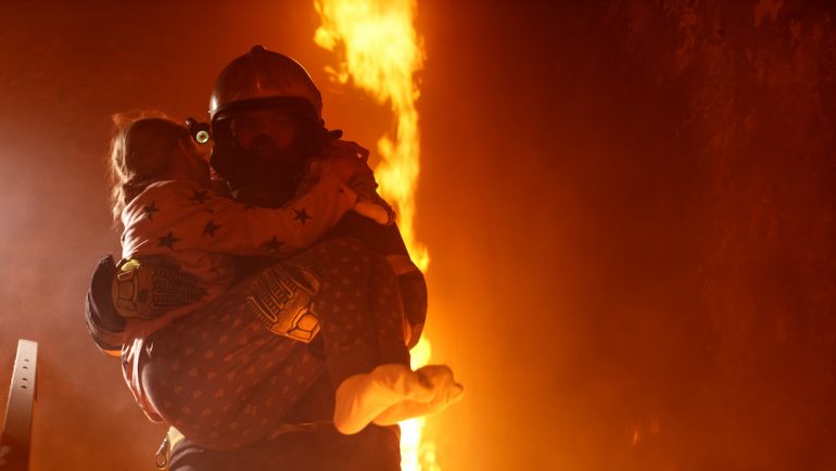 Brave fireman carries girl downstairs in a burning home with open fire after he found her behind a closed bedroom door.