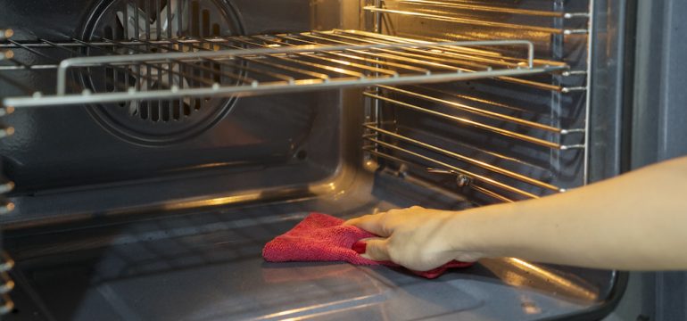 Hand of a woman cleaning up after the self cleaning oven cycle.