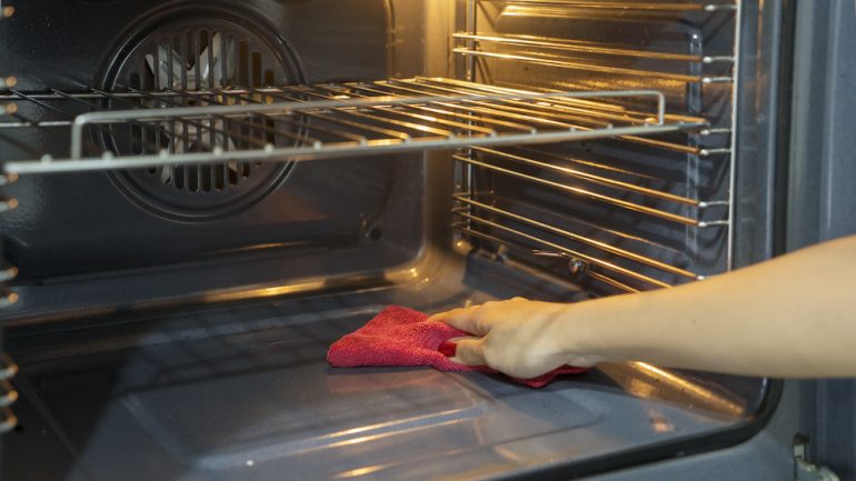 Hand of a woman cleaning up after the self cleaning oven cycle.
