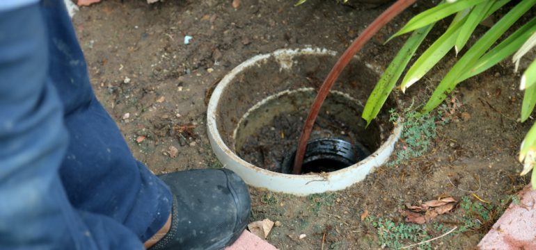 Sewer line cleaning. A plumber uses a sewer snake to clean blockage in a sewer line.