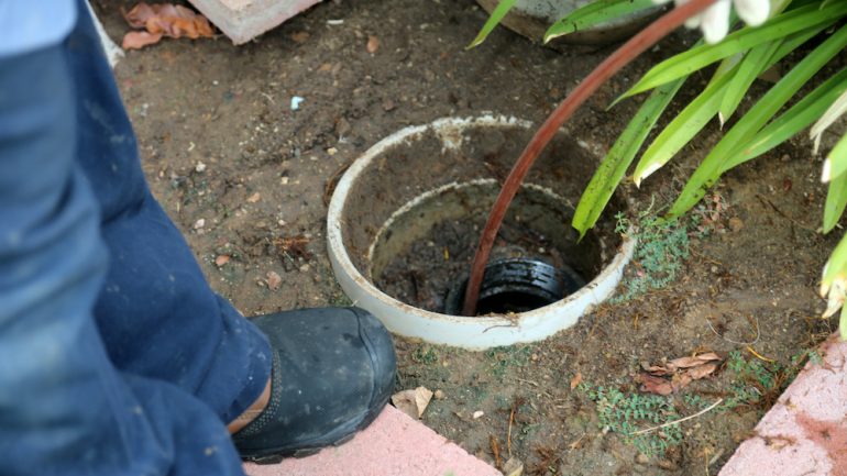 Sewer line cleaning. A plumber uses a sewer snake to clean blockage in a sewer line.