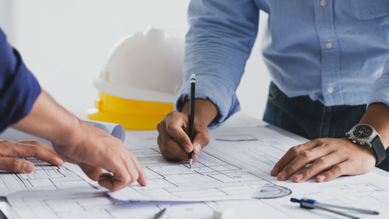 The general contractor for a construction project working with a partner at a desk in a home office.