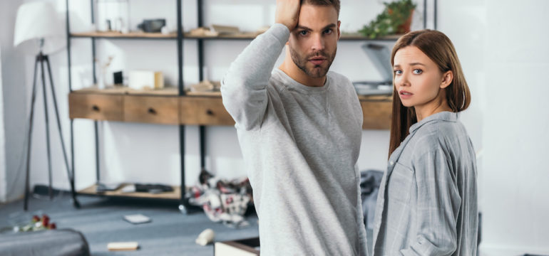 Attractive woman and shocked man after discovering a home burglary.