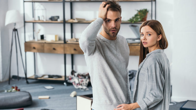 Attractive woman and shocked man after discovering a home burglary.