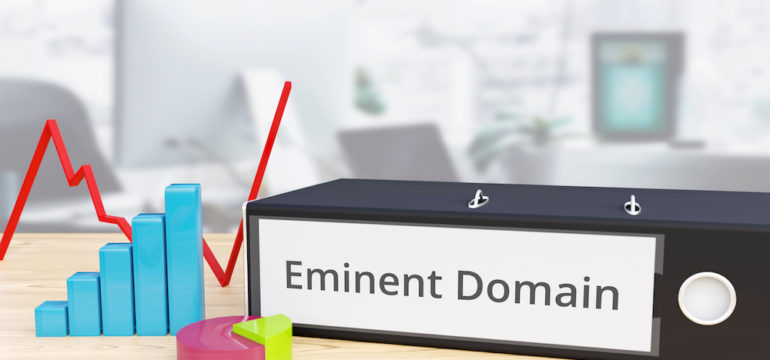 Eminent Domain - Finance/Economy. Folder on a desk with a label beside diagrams.