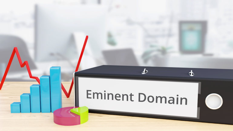 Eminent Domain - Finance/Economy. Folder on a desk with a label beside diagrams.