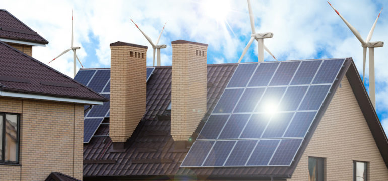 Wind farm near a house with installed solar panels on the roof.