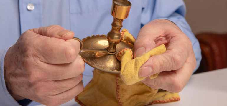 Man shown cleaning candles and polishing brass candlesticks at home.