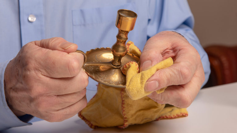 Man shown cleaning candles and polishing brass candlesticks at home.