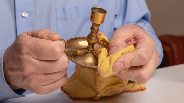Man shown cleaning candles and polishing brass candlesticks at home.