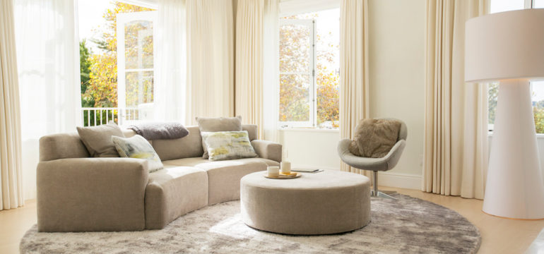 Round carpet under beige curved furniture in living room.