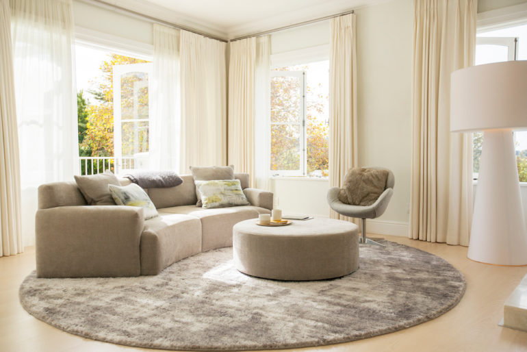 Round carpet under beige curved furniture in living room.