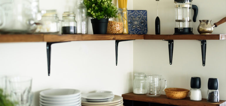 Dishes and decorations on wood open shelves in a white kitchen.