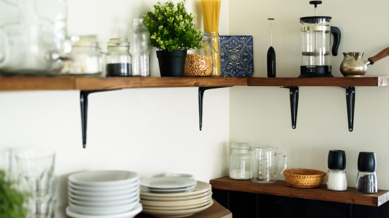 Dishes and decorations on wood open shelves in a white kitchen.