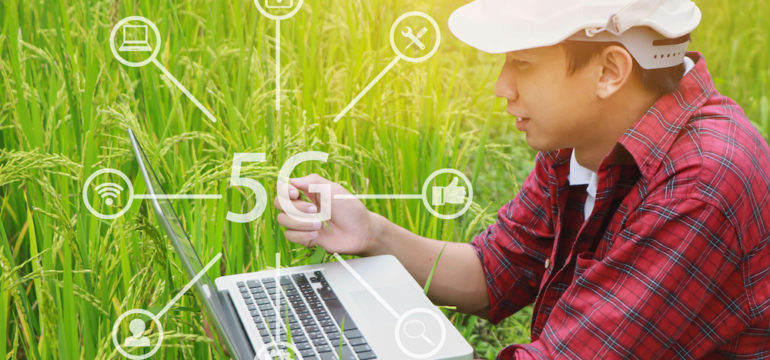 Farmer on rural land connecting to satellite internet service on his laptop in his field.