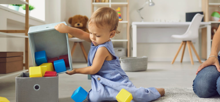 Little boy cleaning up toys and learning to be independent.