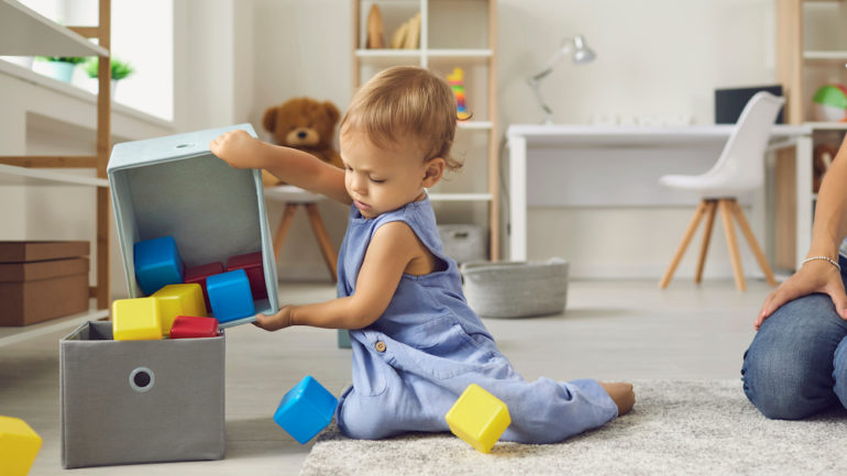 Little boy cleaning up toys and learning to be independent.