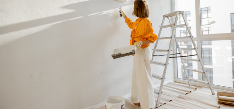 A woman paints the wall in white color to show what to repair before you sell your house.