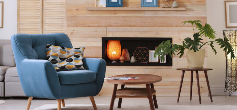 Cozy apartment with rental furniture. There is a blue armchair and coffee table in the foreground.