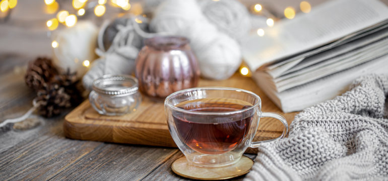 Cozy still life with tea and decorative items, glowing lights in the background to brighten winter doldrums.