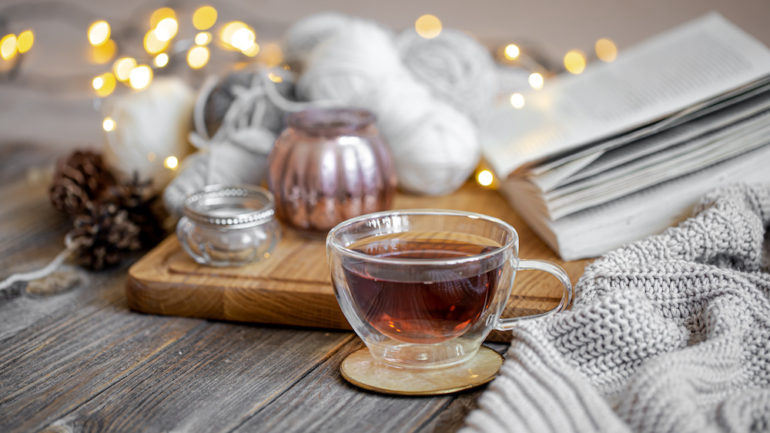 Cozy still life with tea and decorative items, glowing lights in the background to brighten winter doldrums.