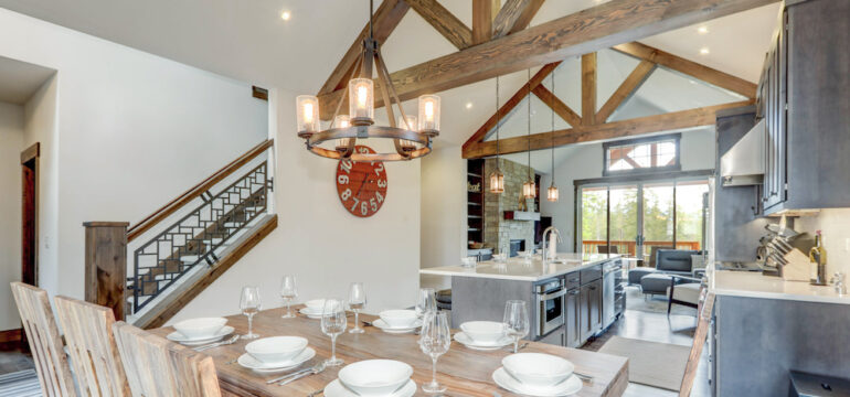 Amazing dining room near modern and rustic luxury kitchen with vaulted ceiling beams, long island with white quartz countertop, and dark wood cabinets.