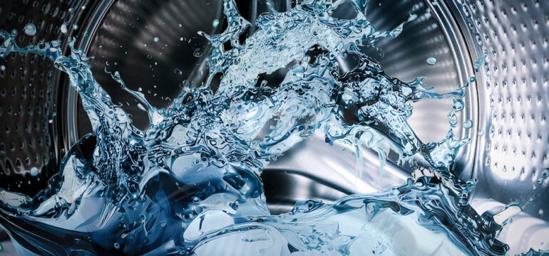 Washing machine drum with clean water flow and splashes.