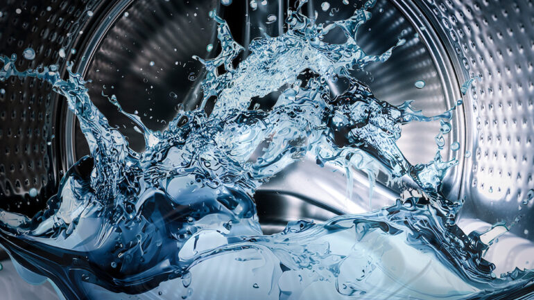 Washing machine drum with clean water flow and splashes.