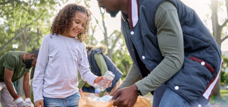 Father is raising eco-friendly kids by showing his daughter how to recycle plastic bottles.