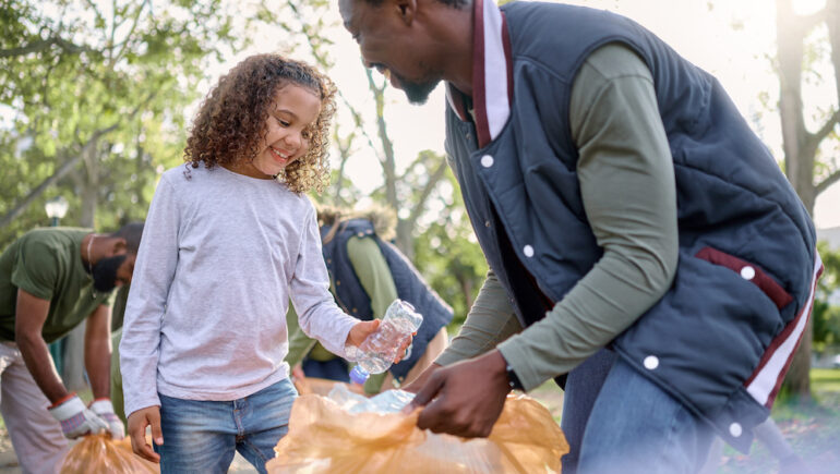 Father is raising eco-friendly kids by showing his daughter how to recycle plastic bottles.