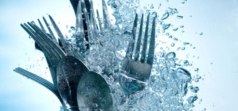 Washing kitchenware in dishwasher with clear water on bubbles background.