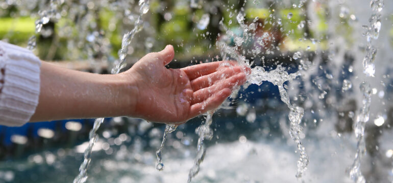 A hand touches clean and fresh water, showing the concept of landowner water rights.