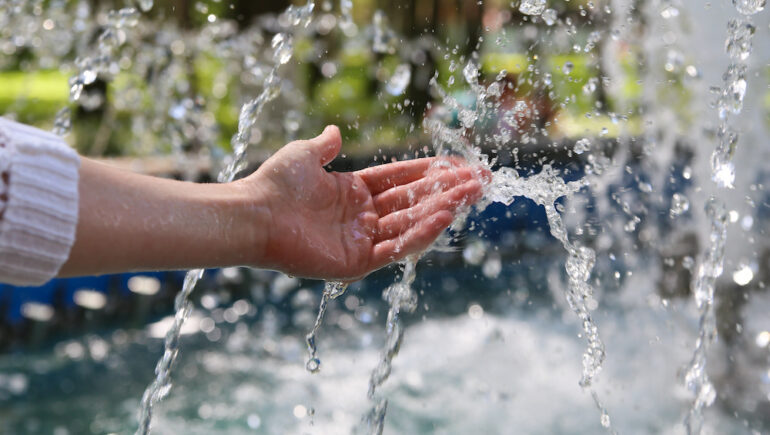 A hand touches clean and fresh water, showing the concept of landowner water rights.