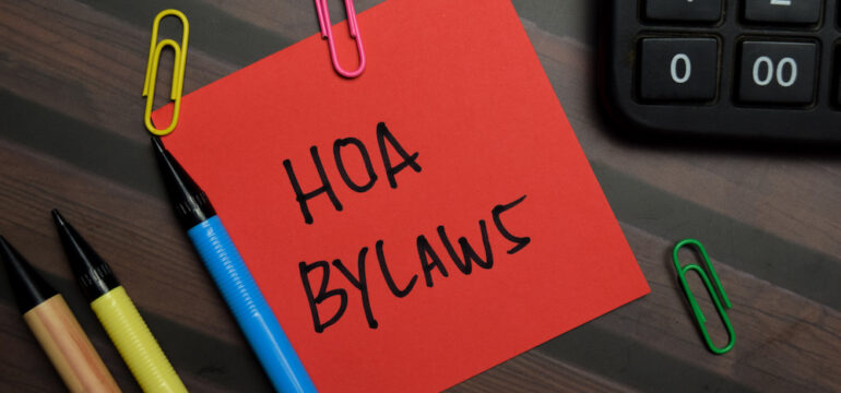 HOA Bylaws are written on sticky notes isolated on a wooden table. Also includes the Architectural Control Committee.